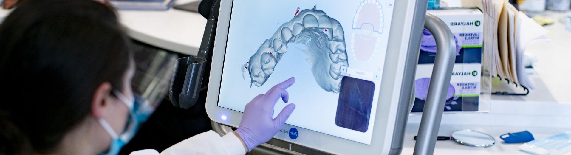 Dental student examines teeth film from computer.